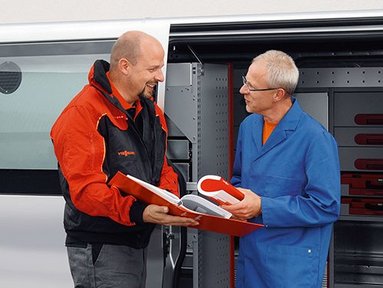 Ein Vissmann Mitarbeiter zeigt einem Kunden, einen Ordner vor einem Firmenbulli